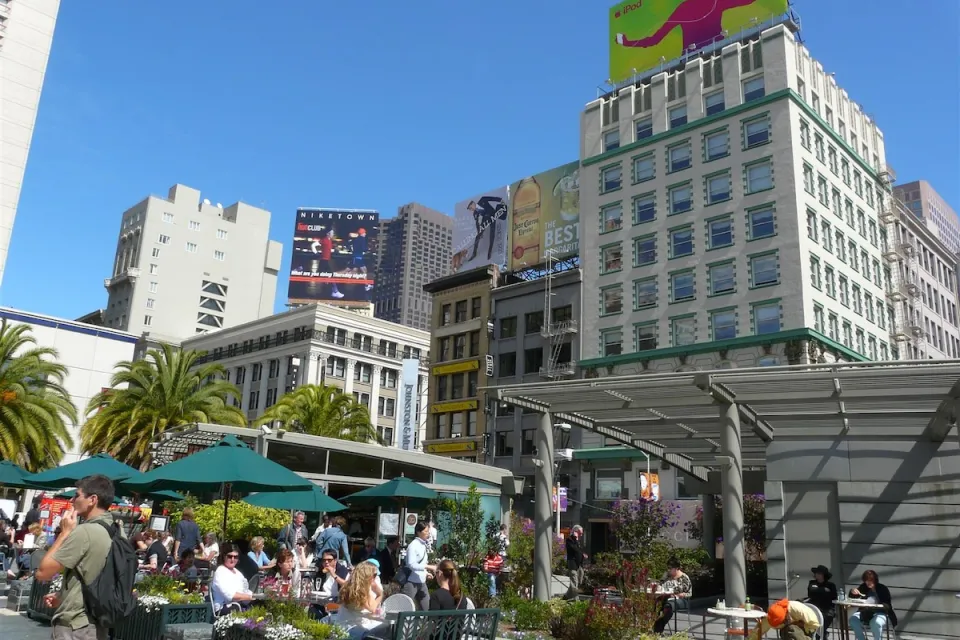 People sitting at outdoor tables with green umbrellas in Union Square, San Francisco.